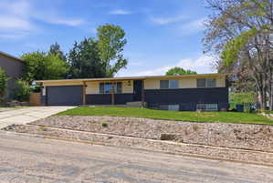 Ranch-style house featuring a front lawn, concrete driveway, and an attached garage