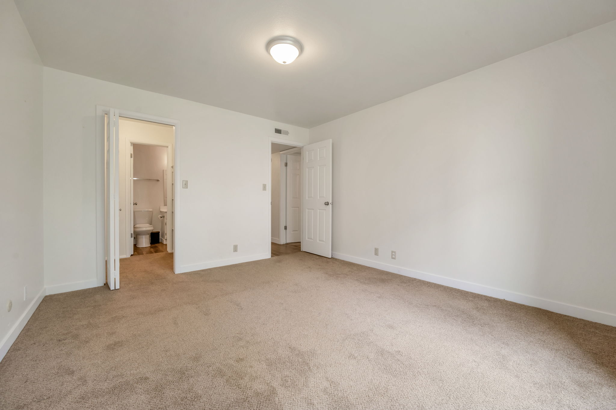 Primary suite/Master bedroom featuring light carpet and ensuite bathroom and walk-in closet