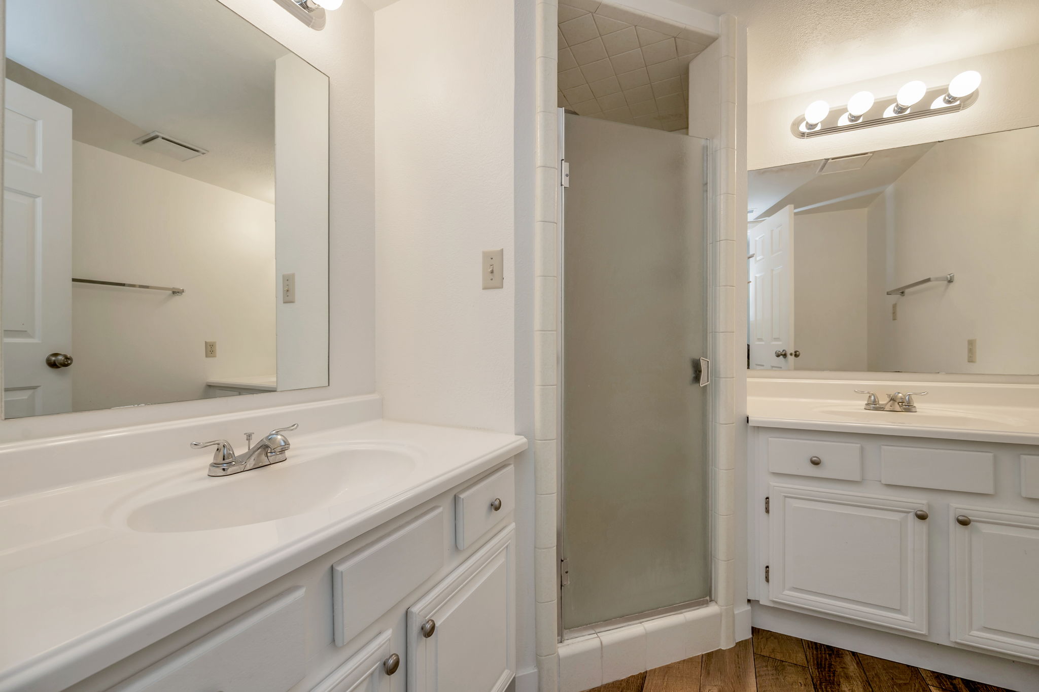 Primary/master bathroom with two vanities, a shower.