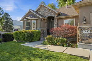Stone and stucco exterior featuring a bay window with copper-finish roofing, an arched entryway, and an outdoor wall lantern