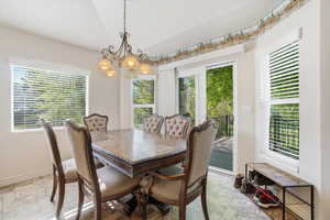 Dining space featuring tile flooring, multiple windows with blinds, a sliding glass door, and a decorative border at the ceiling line