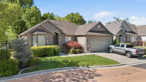 View of front of home with stone siding, stucco siding, a garage, a front yard, and driveway