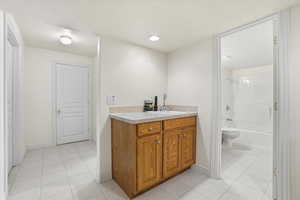 Utility area featuring a wood-finish cabinet with a sink, light-toned countertop, and recessed lighting
