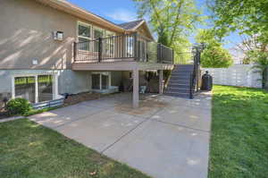 Rear view of property with a wooden deck, stucco siding, and a patio