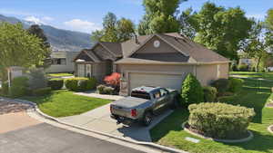 View of front facade with stucco siding, a front yard, a garage, and driveway