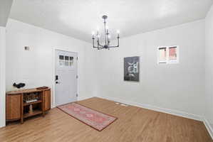 Foyer with a textured ceiling, light wood-style flooring, and a chandelier