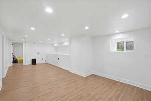 Below grade living room with light wood-style flooring and recessed lighting