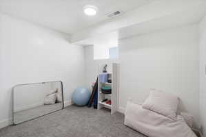 Workout/bedroom room with light colored carpet and a textured ceiling