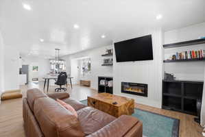 Living room featuring light wood-type flooring, a glass covered fireplace, a textured ceiling