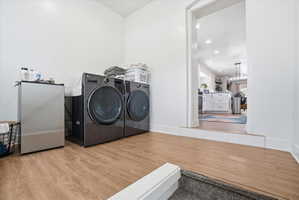 Laundry area featuring light wood-type flooring, separate washer and dryer, and recessed lighting