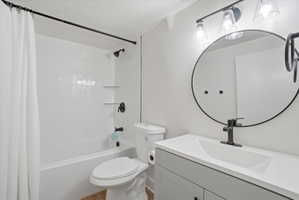 Full bath featuring a textured ceiling, vanity, and shower / bath combo with shower curtain