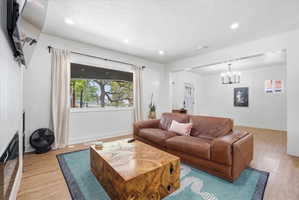 Living area with light wood-type flooring, a textured ceiling, and hanging lights