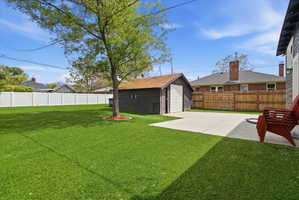Fenced backyard with an outdoor structure, a garage, and concrete driveway