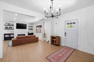 Entrance foyer with a chandelier, a textured ceiling, light wood-style flooring, plenty of natural light, and a large fireplace