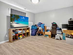 Recreation room featuring light wood-style floors and a textured ceiling