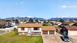 Raised ranch featuring brick siding, a mountain view, a residential view, a front lawn, and concrete driveway