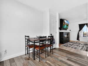 Dining space featuring light wood-style floors and a glass covered fireplace
