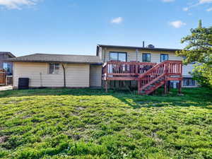 Back of property with a lawn and a wooden deck