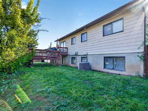 Back of property featuring a lawn and a wooden deck