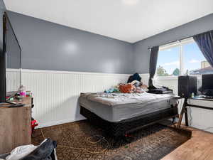 Bedroom featuring wood finished floors and a wainscoted wall