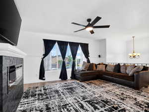Living area featuring wainscoting, hanging lights, wood finished floors, a ceiling fan, and a brick fireplace
