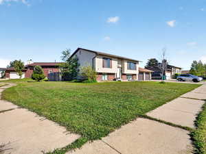 Bi-level home featuring brick siding, a garage, and a front yard