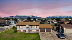 View of front of property featuring a mountain view, brick siding, driveway, and a residential view