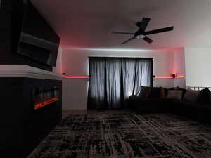 Living area featuring ceiling fan, a glass covered fireplace, wood finished floors, a textured ceiling, and wainscoting