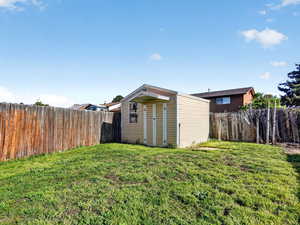 Fenced backyard featuring a storage shed