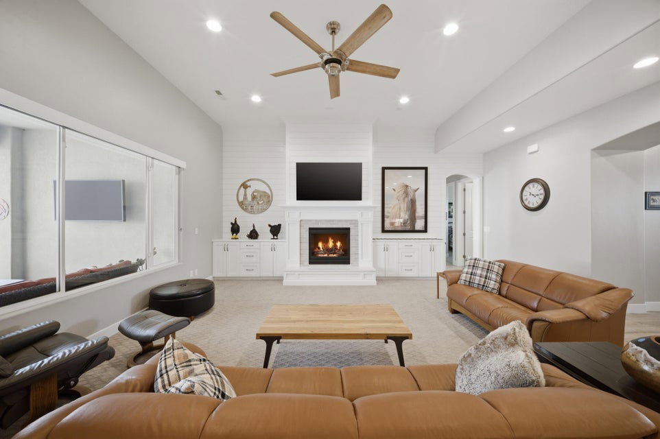 Living area with recessed lighting, a ceiling fan, light carpet, a warm lit fireplace, and arched walkways