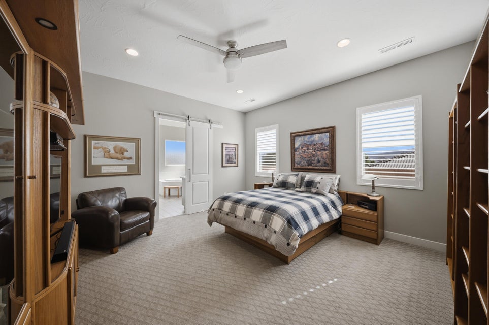 Bedroom with carpet floors, ceiling fan, a barn door, recessed lighting, and ensuite bath