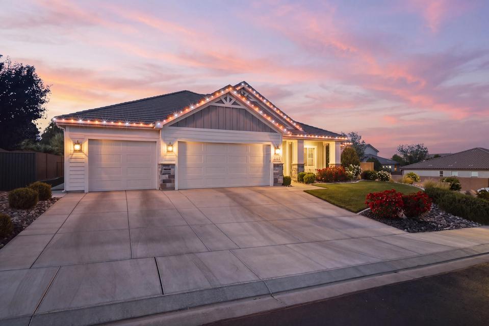 View of front of property featuring an attached garage, concrete driveway, a lawn, and a tiled roof