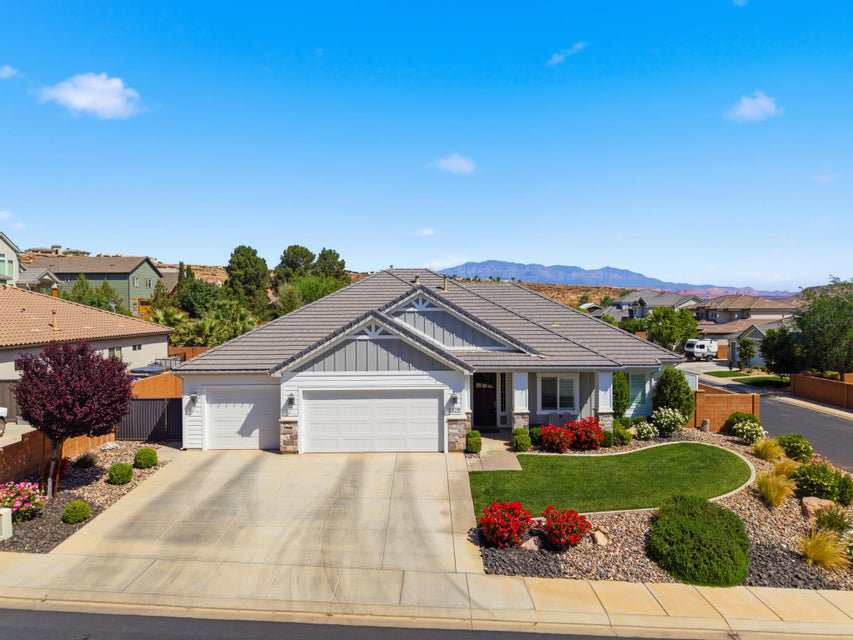 Craftsman-style house featuring an attached garage, stone siding, board and batten siding, a residential view, and driveway