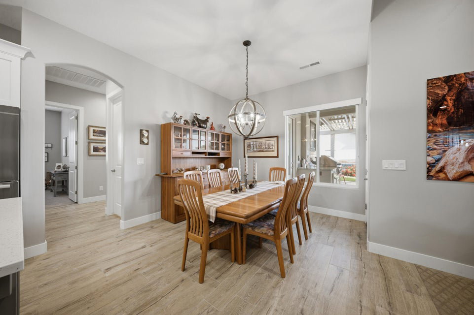 Dining room with light wood-style flooring, arched walkways, and a chandelier