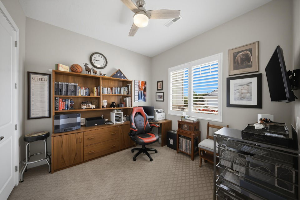 Office space featuring light carpet and a ceiling fan