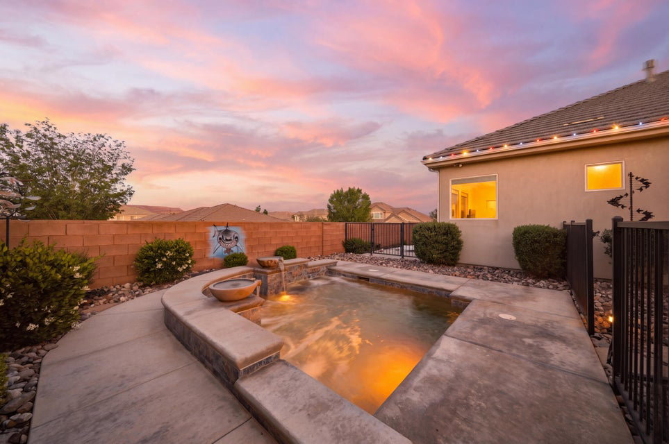 Pool at dusk featuring an in-ground hot tub, a fenced backyard, and a patio area