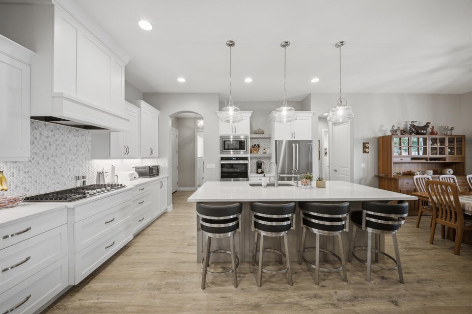 Kitchen featuring an island with sink, a kitchen breakfast bar, pendant lighting, white cabinets, and stainless steel appliances