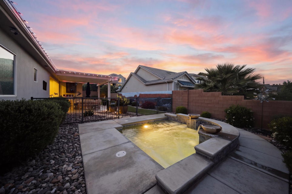 Pool at dusk with a fenced backyard and a patio