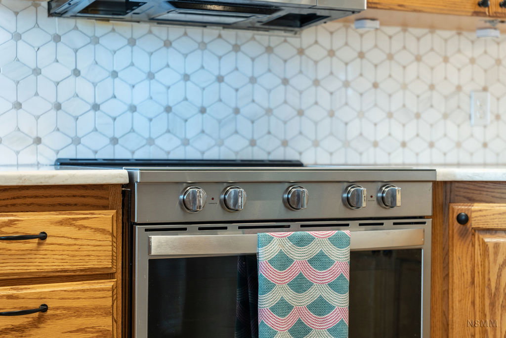 Kitchen view of stainless steel range with electric stovetop and ventilation hood