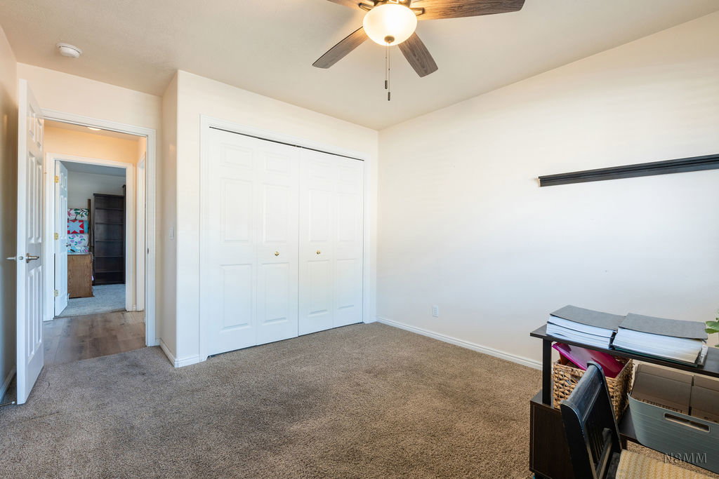 Office area featuring dark colored carpet and a ceiling fan