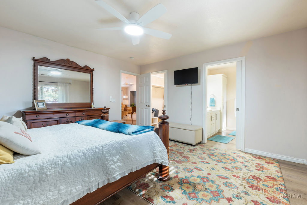 Bedroom with light wood-type flooring, a ceiling fan, and a walk in closet