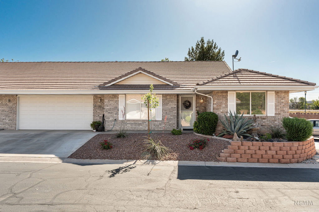 Ranch-style home featuring a garage, a porch, brick siding, and concrete driveway