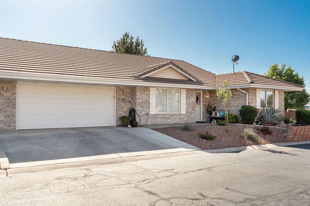 Single story home featuring a garage, driveway, a tile roof, and brick siding