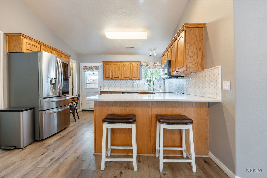 Kitchen with a peninsula, stainless steel fridge, a breakfast bar, and light wood-style flooring