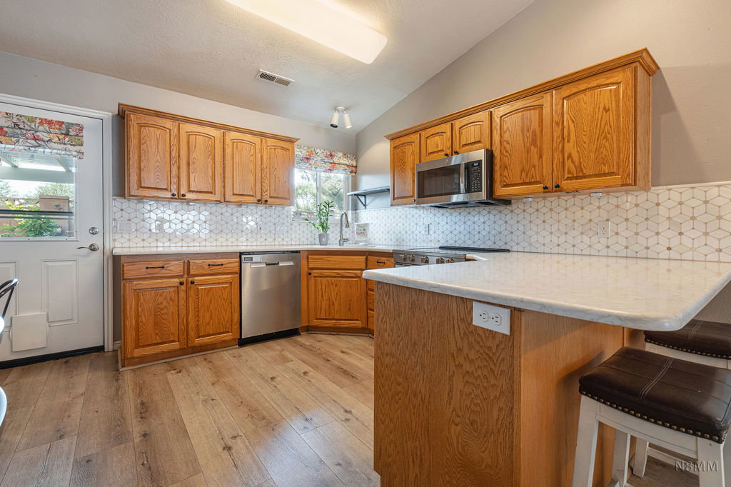 Kitchen featuring a peninsula, vaulted ceiling, wood finish cabinets, a kitchen breakfast bar, and light wood finished floors