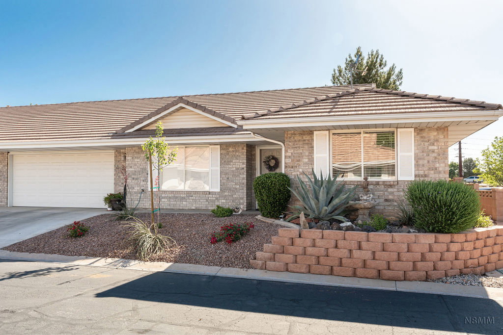 Ranch-style home featuring an attached garage, concrete driveway, brick siding, and a tile roof