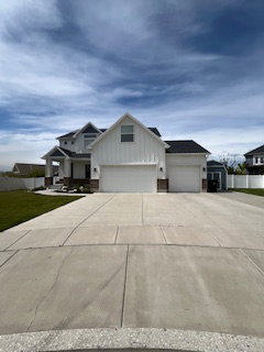 Modern inspired farmhouse with board and batten siding, concrete driveway, a garage, and a front yard