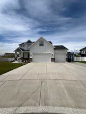 Modern inspired farmhouse with board and batten siding, concrete driveway, a garage, and a front yard