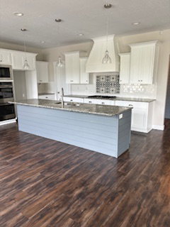 Dual tone kitchen featuring a large island, dark wood-type flooring, decorative light fixtures, dark stone counters, and dual tone cabinets