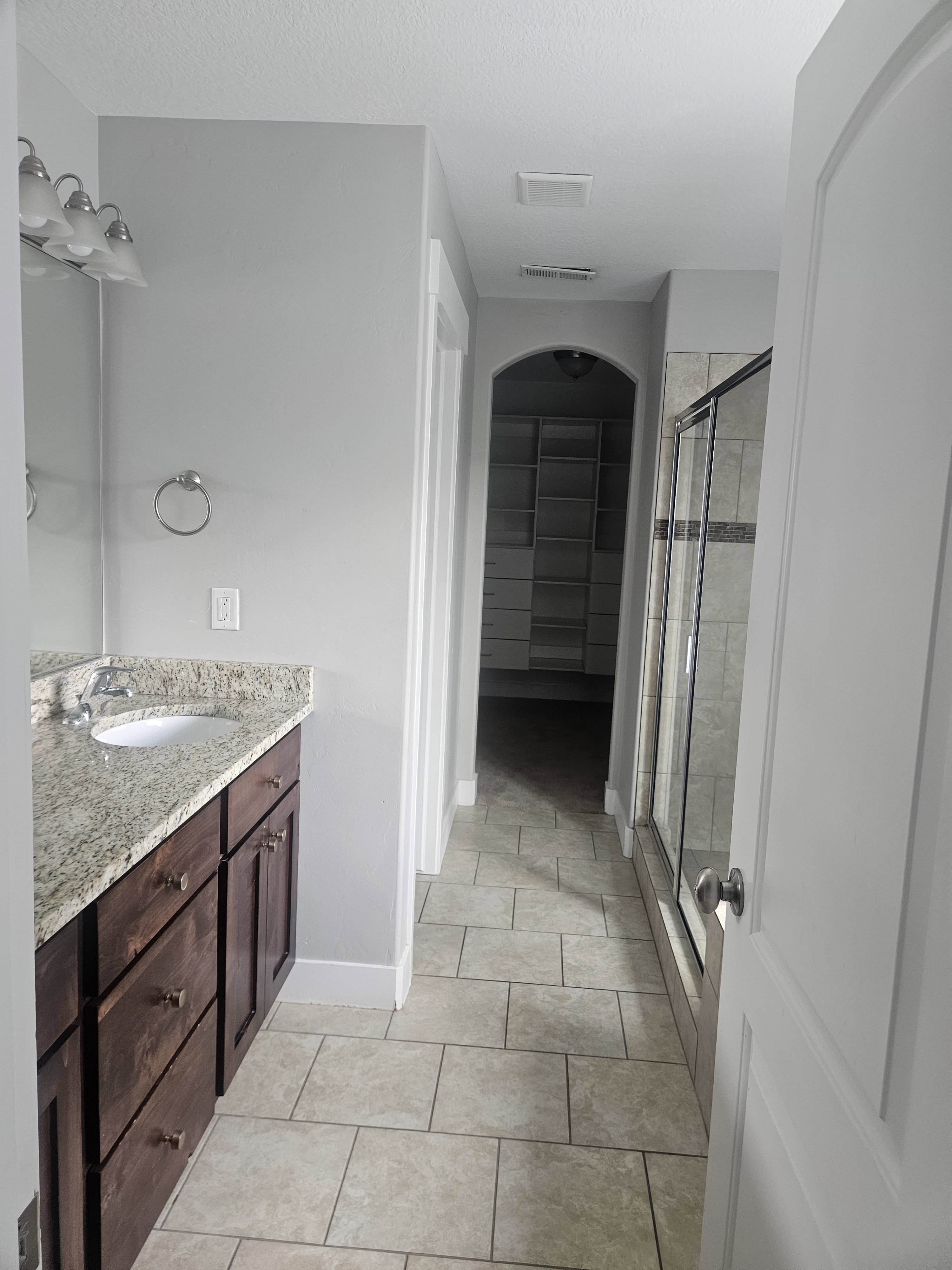 Full bath featuring vanity, a stall shower, light tile patterned floors, and a walk in closet